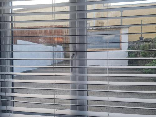 a window with blinds on it with a dog looking through it at Bright and Spacious Home Near Bridgend Town Centre in Bridgend