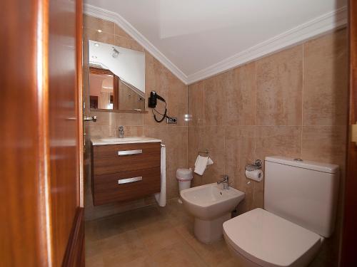 a bathroom with a white toilet and a sink at Pensión Residencia A Cruzán in Noalla