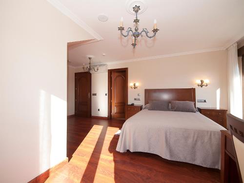 a bedroom with a bed and a chandelier at Pensión Residencia A Cruzán in Noalla