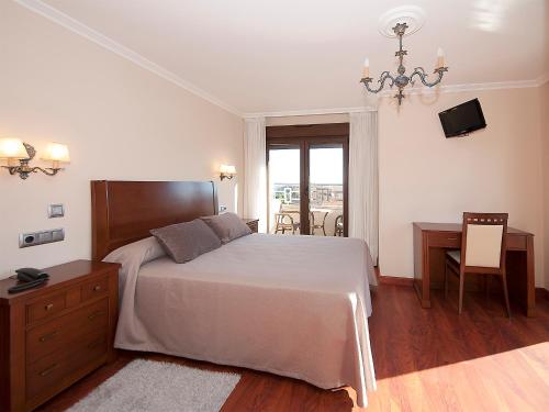 a bedroom with a bed and a table and a desk at Pensión Residencia A Cruzán in Noalla