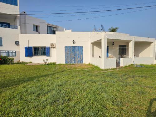 una casa blanca con una puerta azul y un patio en Nassime 1, en Cabo Negro