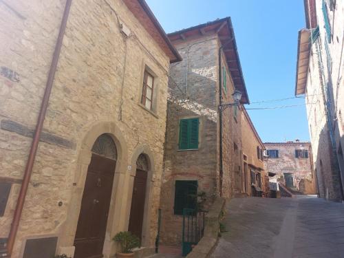 an old stone building with green shutters on a street at Tuscan Hilltop Getaway in Montecastelli Pisano