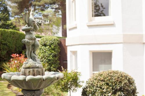 a statue of a girl on a fountain in front of a house at Washington House Hotel in Bournemouth