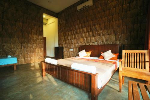 a bedroom with a bed and a wooden wall at Rise & Set Arugam bay in Arugam Bay