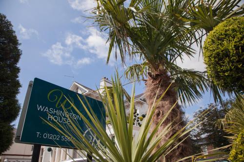 a palm tree in front of a building with a sign at Washington House Hotel in Bournemouth