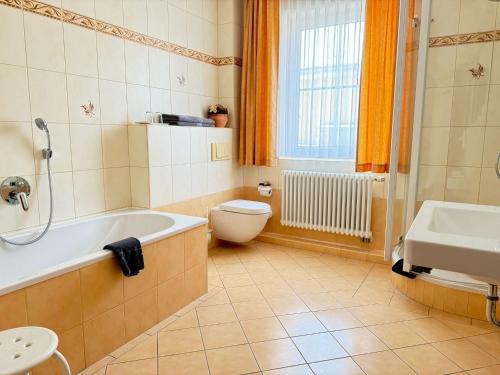 a bathroom with a tub and a toilet and a sink at Hotel am Hafen Havelberg in Havelberg