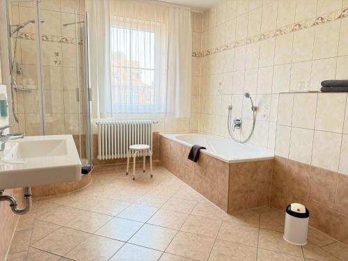 a bathroom with a tub and a shower and a sink at Hotel am Hafen Havelberg in Havelberg