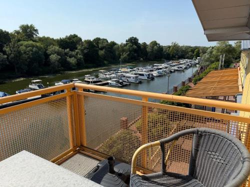 a man sitting on a balcony looking at a marina at Hotel am Hafen Havelberg in Havelberg