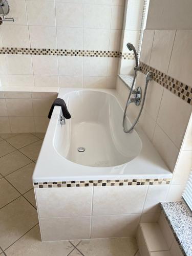 a white bath tub with a shower in a bathroom at Hotel am Hafen Havelberg in Havelberg