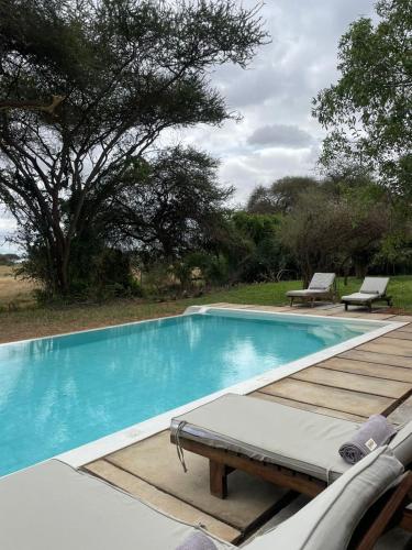 a swimming pool with a wooden deck and a bench at Ashnil Aruba Lodge in Tsavo