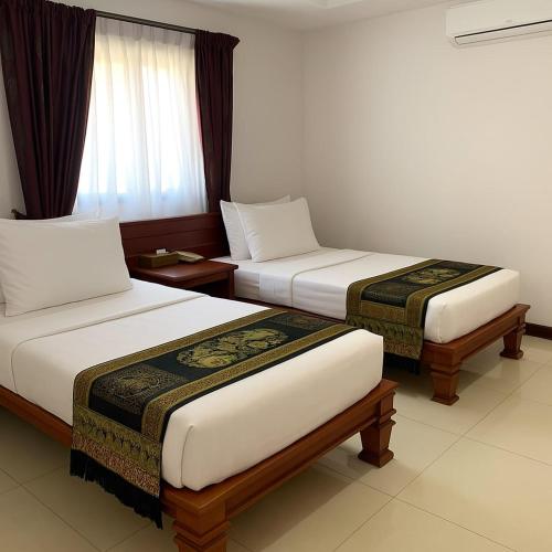 a hotel room with two beds and a window at Hawaii Beach Bungalows in Sihanoukville
