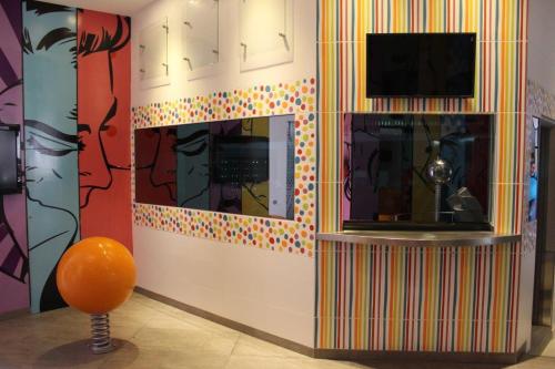 a room with a tv and a wall with a painting at Oh! Oriente Hotel in Mexico City