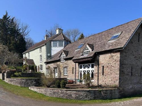 a large stone house with a stone wall at Escape to the Hillis in Llandefalle