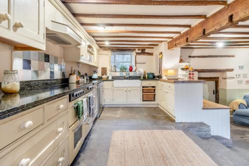 a large kitchen with white cabinets and an island at Escape to the Hillis in Llandefalle