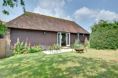 a house with a yard with a swing at Wagon Lodge at Forstal Farm in Tenterden