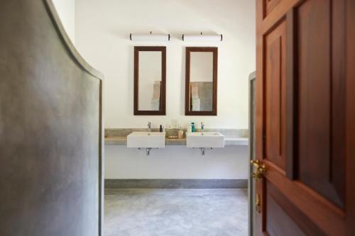 a bathroom with two sinks and two mirrors at Kalukanda House in Weligama