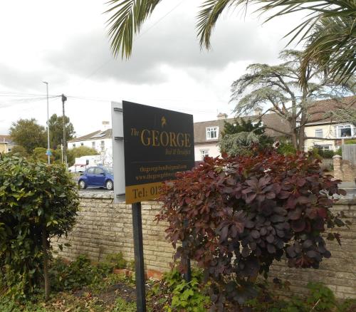 a sign in front of a house with a building at The George B & B in Weymouth