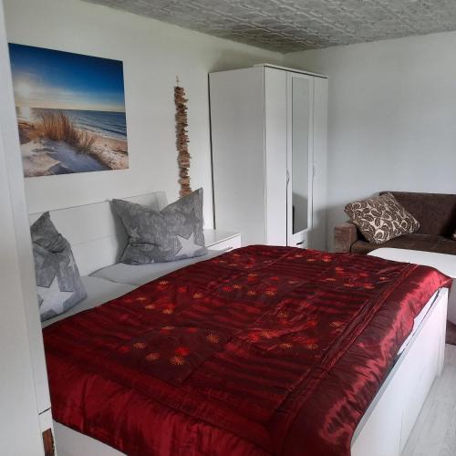 a bedroom with a bed with a red comforter at Bungalow Mika und Lizzy in Koserow