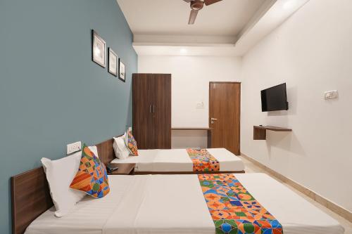 two beds in a room with a tv on the wall at FabHotel Skyline in Bengaluru