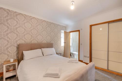 a bedroom with a large white bed and a bathroom at River View at Hanlith Hall in Airton