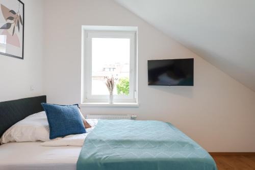 a bedroom with a bed with blue pillows and a window at CitySuites Salzburg in Salzburg