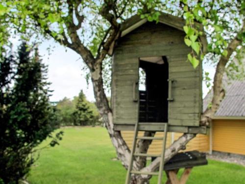 a tree house with a ladder in a yard at 4 star holiday home in Dannemare in Dannemare