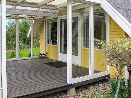 a porch of a yellow house with glass doors at 4 star holiday home in Dannemare in Dannemare