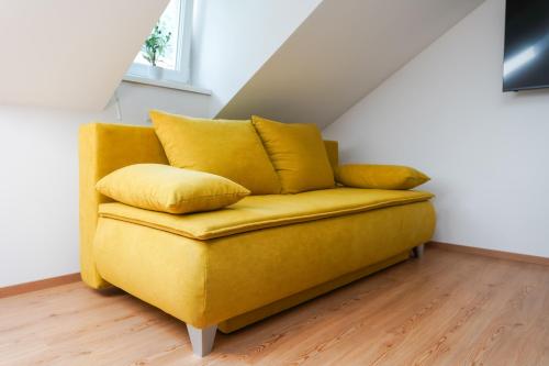 a yellow couch with pillows in a room at CitySuites Salzburg in Salzburg