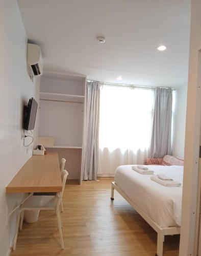 a bedroom with a bed and a desk and a window at K Home Asok in Bangkok