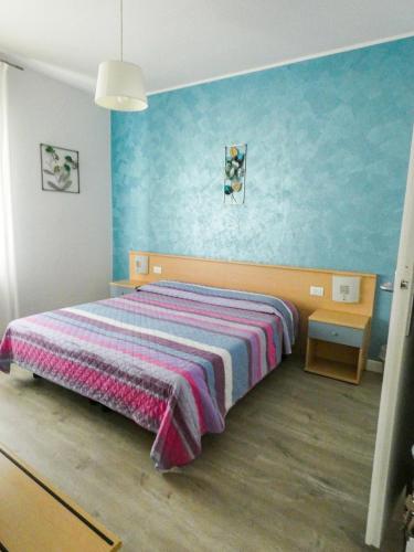 a bedroom with a bed with a striped blanket at Hotel Alpino in Malcesine