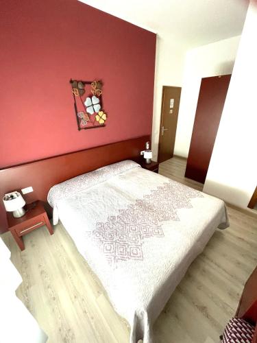 a bedroom with a bed with a red wall at Hotel Alpino in Malcesine