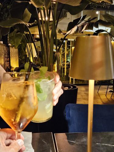 a person holding two drinks on a table at Hotel Suites Feria de Madrid in Madrid