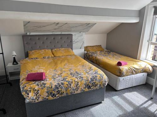 a bedroom with two beds with yellow and pink sheets at Triple room Private Bath Near LFC Free Street Parking No Breakfast in Liverpool