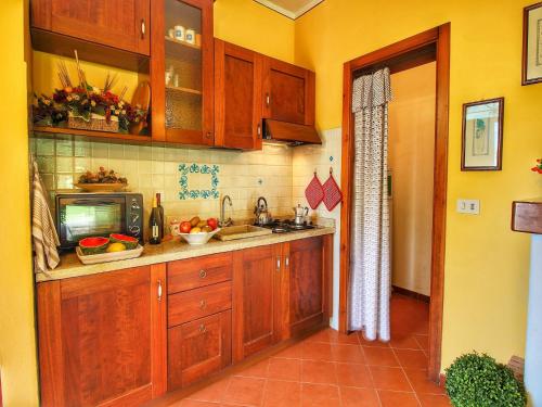 a kitchen with wooden cabinets and a sink and a tv at Apartment in Tuscany near Lake Trasimeno in Valiano