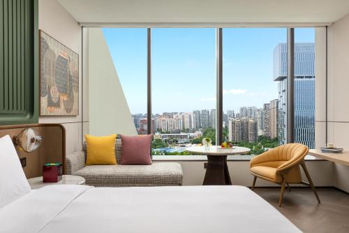 Un dormitorio con una cama, una silla y una mesa. en Hotel Indigo Chengdu Financial City, en Chengdú