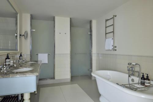 a white bathroom with a tub and a sink at Waldorf Astoria Amsterdam in Amsterdam