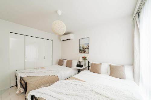 twee bedden in een slaapkamer met witte muren bij Brand New Luxury Suite 7 min to Omotesando 2 min to Shibuya in Tokyo