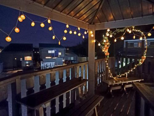 a porch with lights and a bench on a deck at Orange Cabin Inn far from station in Fujikawaguchiko