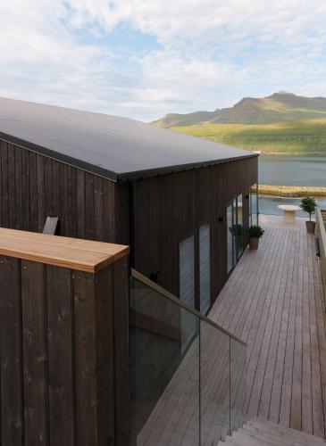 a house with a deck with a view of the water at Hotel Vík - 3 BR Wellness Townhouses with Sauna, Jacuzzi & Panoramic Views in Haldarsvík