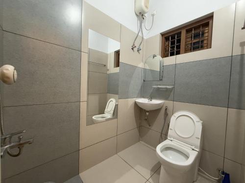 a small bathroom with a toilet and a sink at Coral Shores villa in Varkala