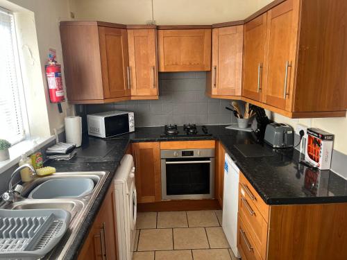 a small kitchen with wooden cabinets and a sink at 101 - Room 2 - Uplands in Sketty