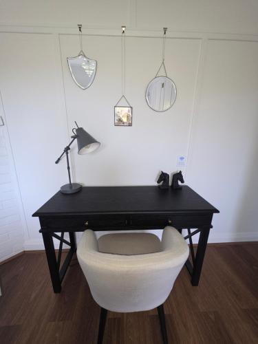 un bureau noir avec une chaise blanche et une lampe dans l'établissement Gladbyrne, à Braidwood