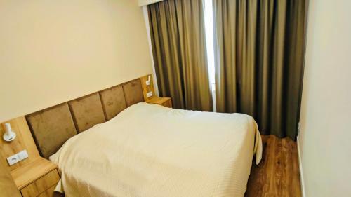 a small bedroom with a bed and a window at Baltic Breeze Apartamenty in Kołobrzeg