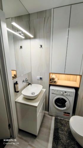 a bathroom with a sink and a washing machine at Baltic Breeze Apartamenty in Kołobrzeg