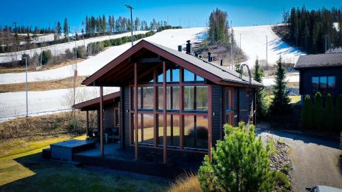une petite maison avec des fenêtres en verre et une colline enneigée dans l'établissement Villa Lumikki 1&2 - 16 hlö, Both villas, Luoteis-Himos Ski-inout, à Jämsä
