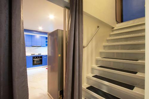 a staircase leading to a kitchen with blue cabinets at บ้านอิ่มสุข in Ban Bua Phut
