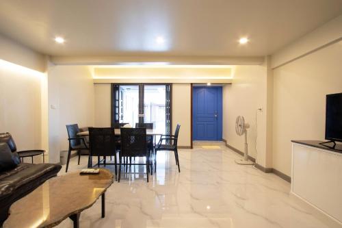 a living room with a table and a blue door at บ้านอิ่มสุข in Ban Bua Phut