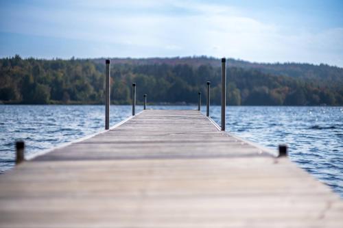 a wooden pier sticking out over a large body of water at SPA and Lake - Chalet le Relaxarium in Sainte-Germaine-du-Lac-Etchemin