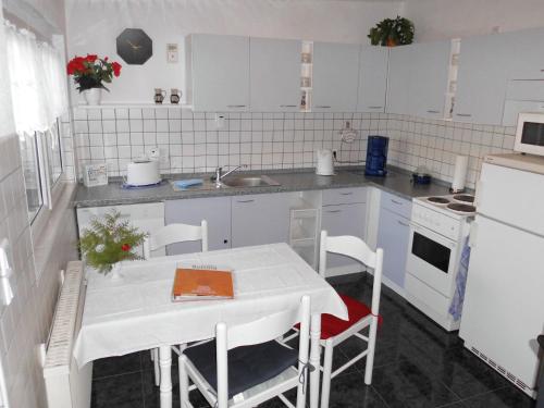 a white kitchen with a table and a sink at Charmantes Ferienhaus Storchenblick in Kremmen