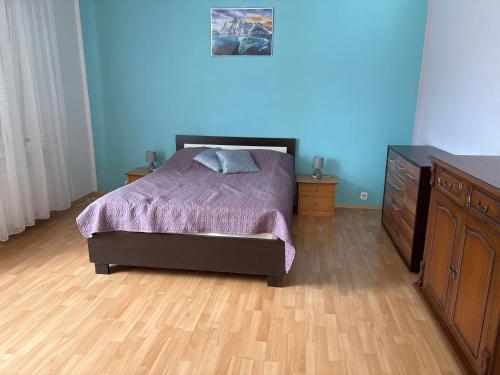 a bedroom with a bed and a dresser and blue walls at Apartament pod Książem in Świebodzice